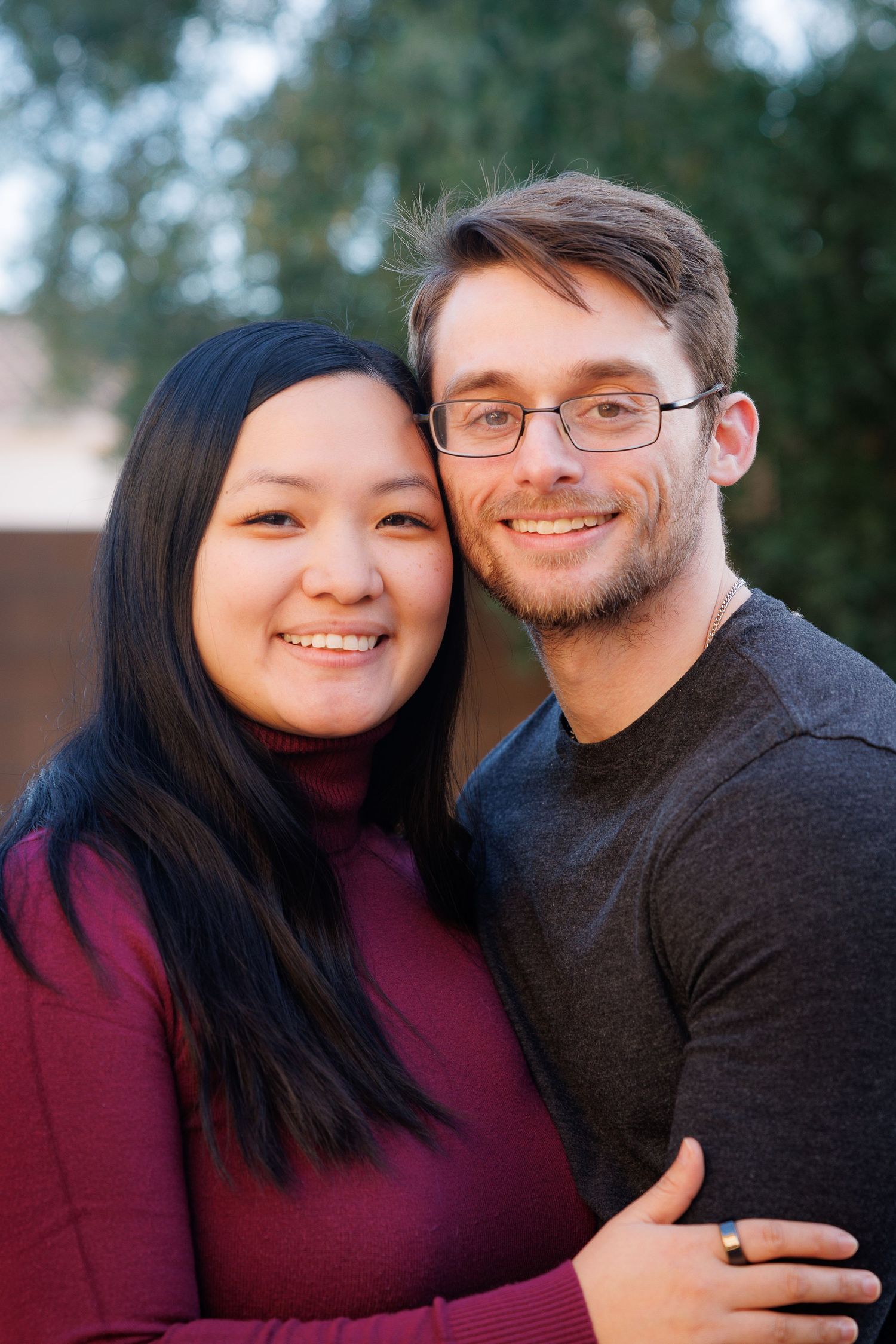 A couple in casual attire share affectionate moments in an outdoor portrait photo.