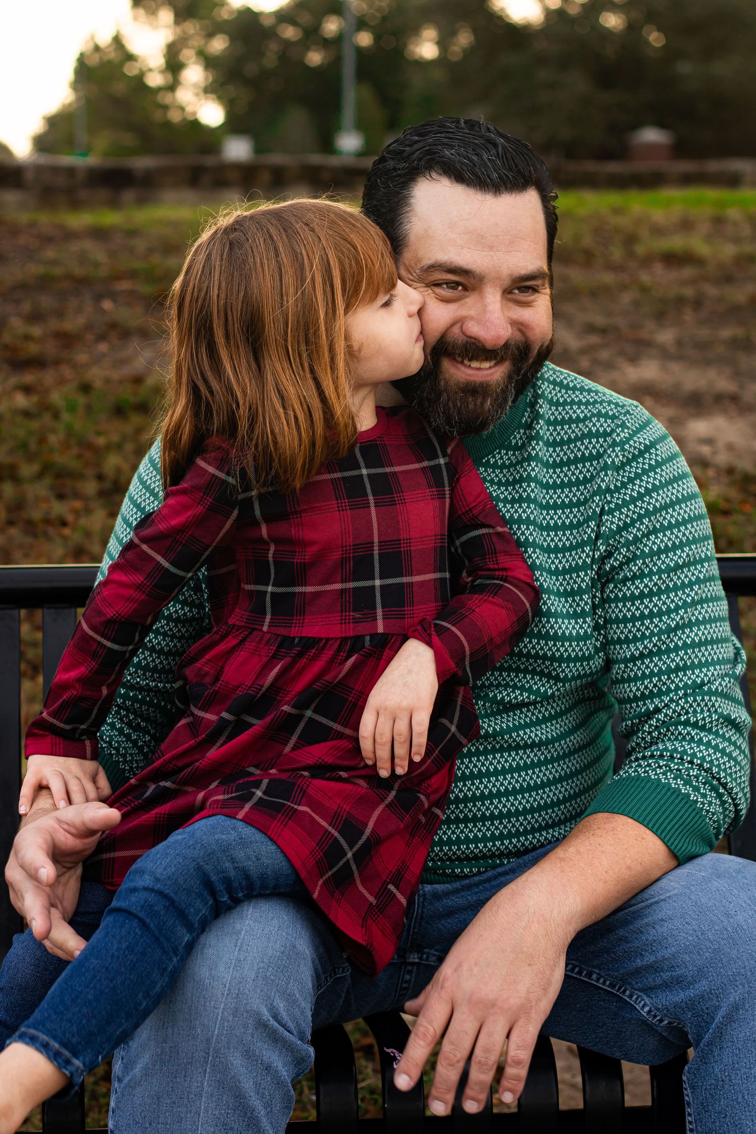 A tender family moment captured on a wooden bench outdoors.