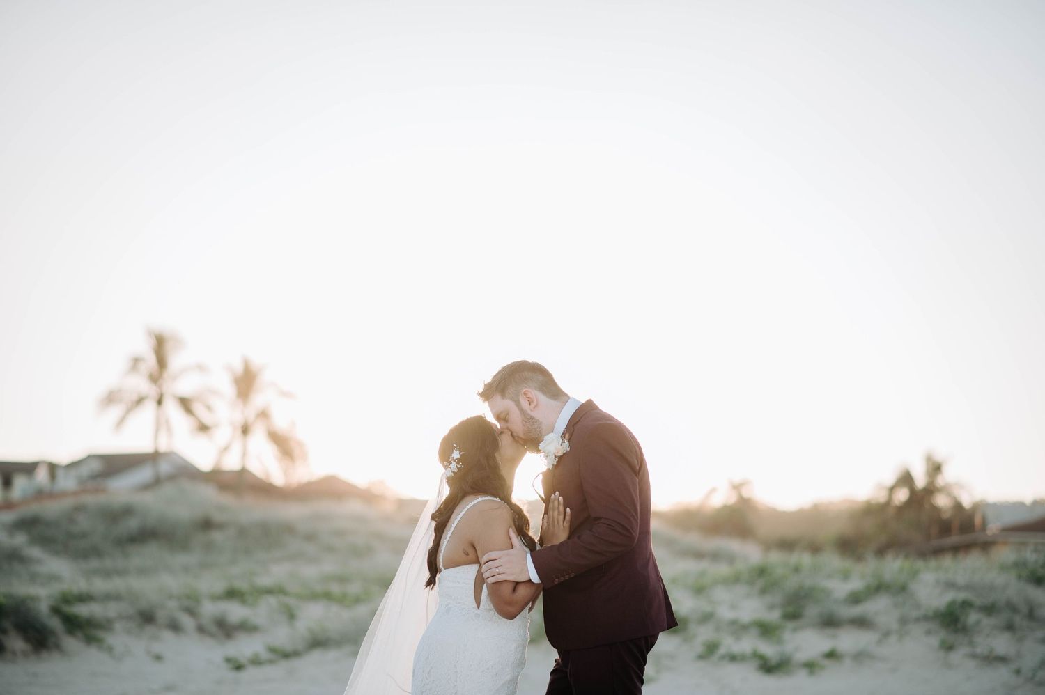 Romantic sunset beach wedding portrait with palm trees in background.