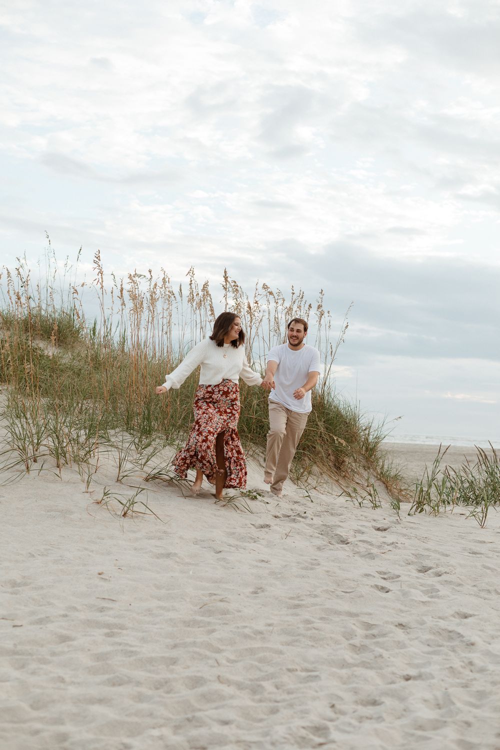 Beach photoshoot sequence showing couple descending sandy dunes near ocean.
