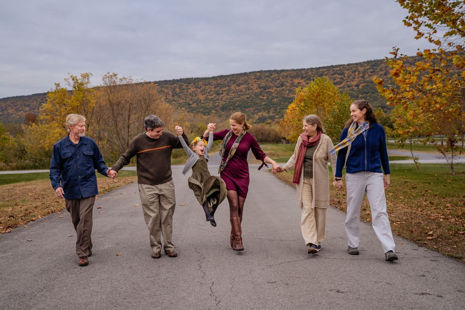 A group of people walking together outdoors on a path during autumn with colorful fall foliage in the background.