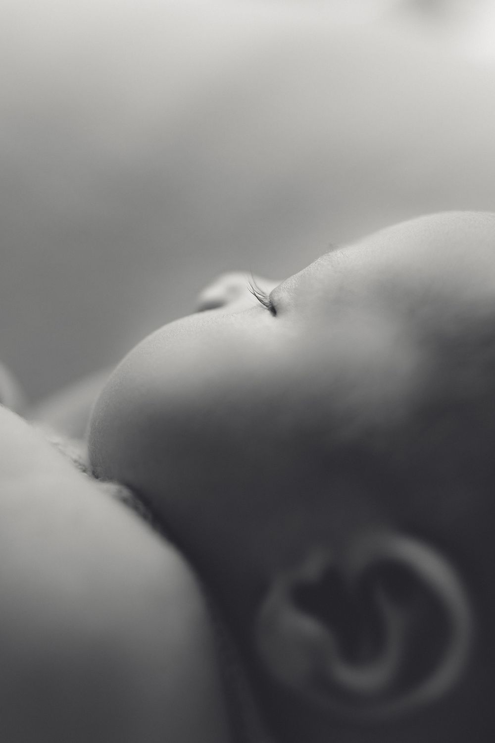 Newborn baby’s tiny face in soft natural light, beautiful long eyelashes, captured in a lifestyle newborn session. Westport NZ