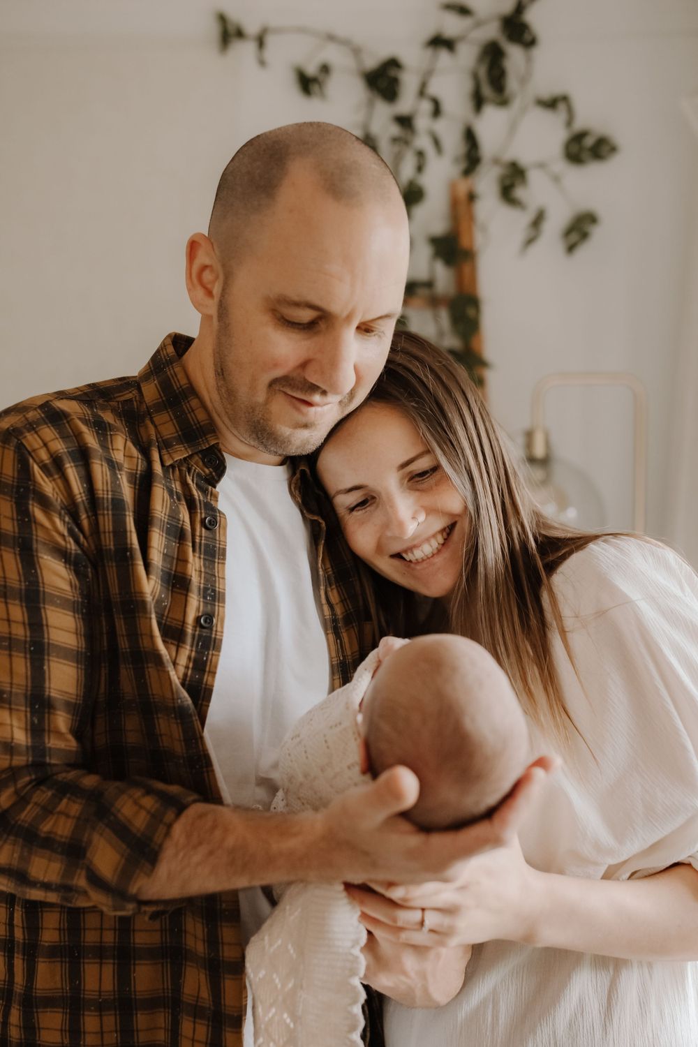 Parents cuddling their newborn baby during a cozy in-home lifestyle photography session in Westport.
