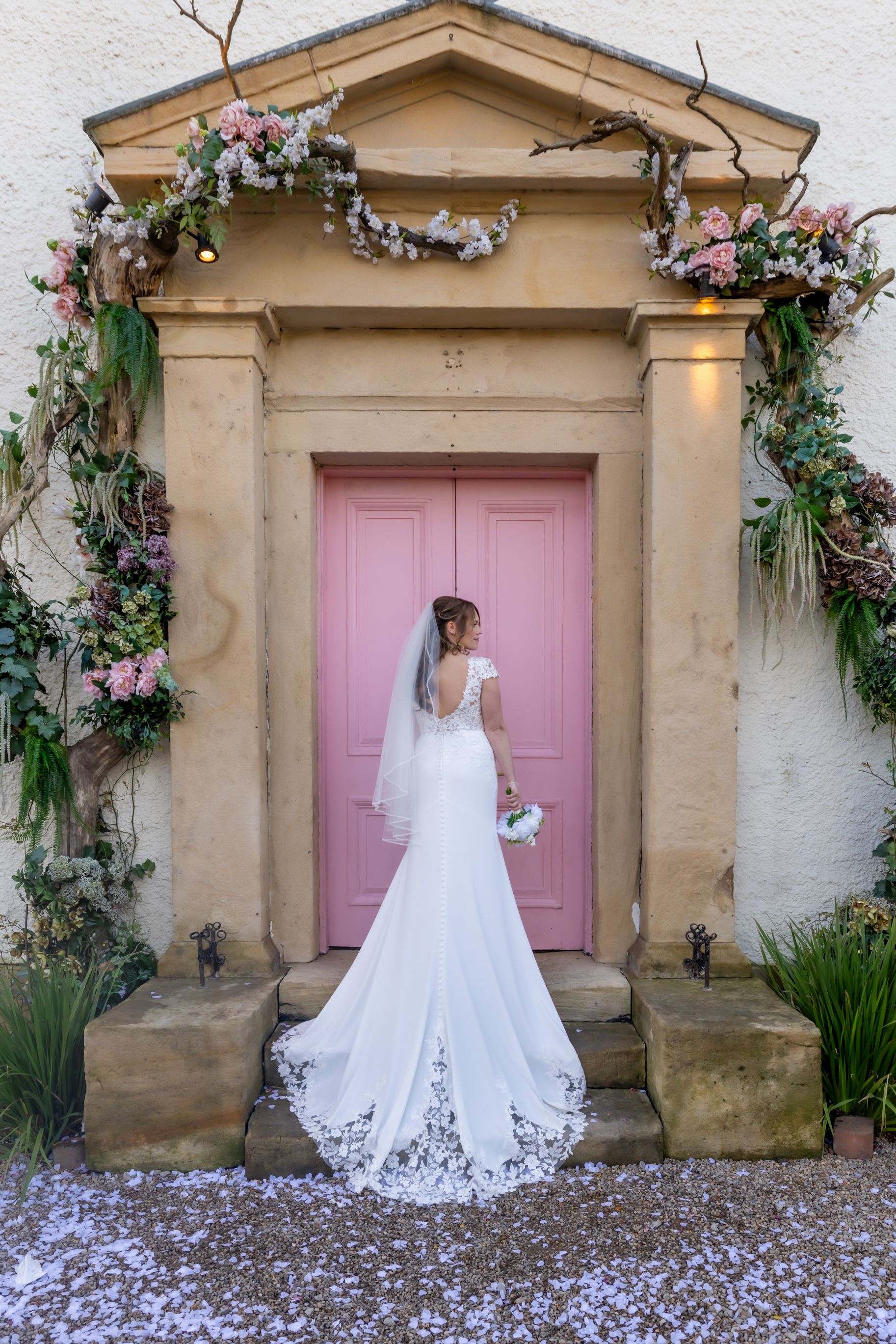 A romantic bridal photoshoot in front of a stone building with a pink door and floral decorations. Croft Hotel, Darlington Casual Captures