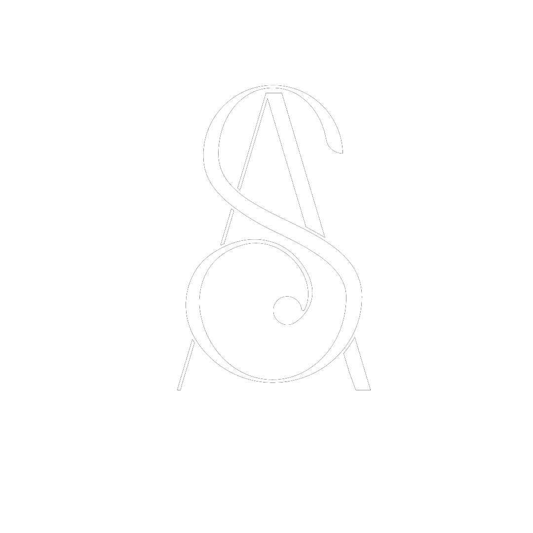 Professional photographer in black blazer holding camera against light blue background.