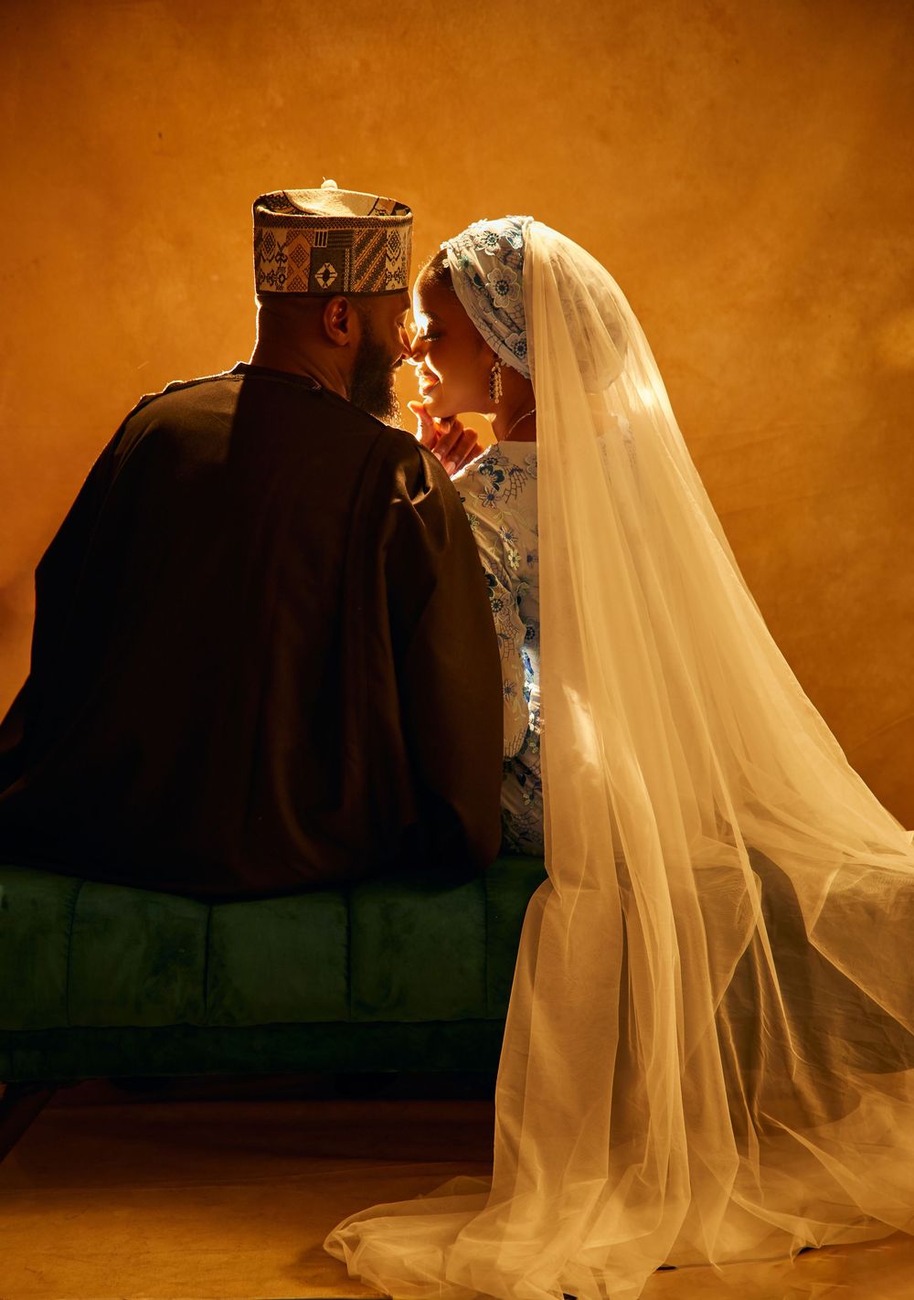 Traditional wedding couple in cultural attire sharing intimate moment against warm background.