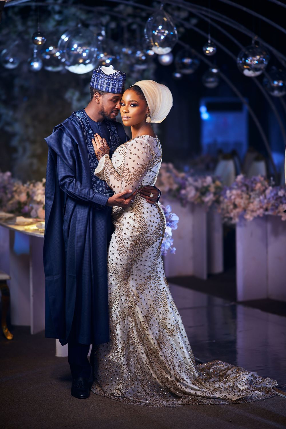 Elegant couple in traditional formal wear posing at glamorous wedding reception.