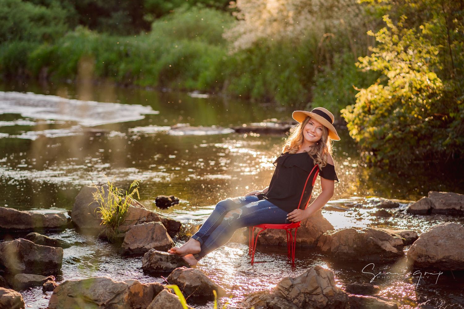 Scenic creek photography session with golden sunlight filtering through trees and flowing water.