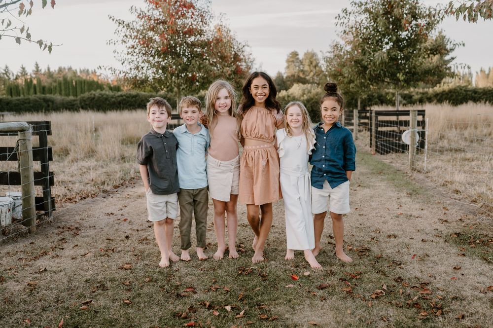 Small group poses together for a casual outdoor portrait in a rustic field setting.
