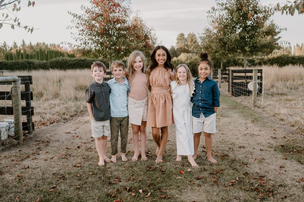 Group stands together for a casual portrait session in a natural outdoor setting at sunset.
