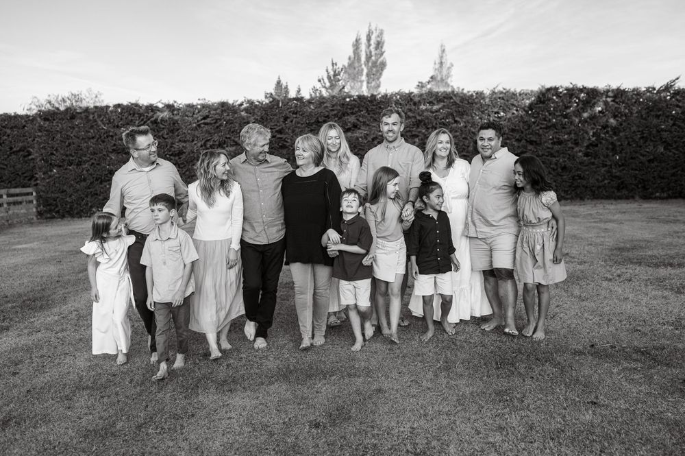 Black and white portrait of extended family gathered together outdoors on grass.