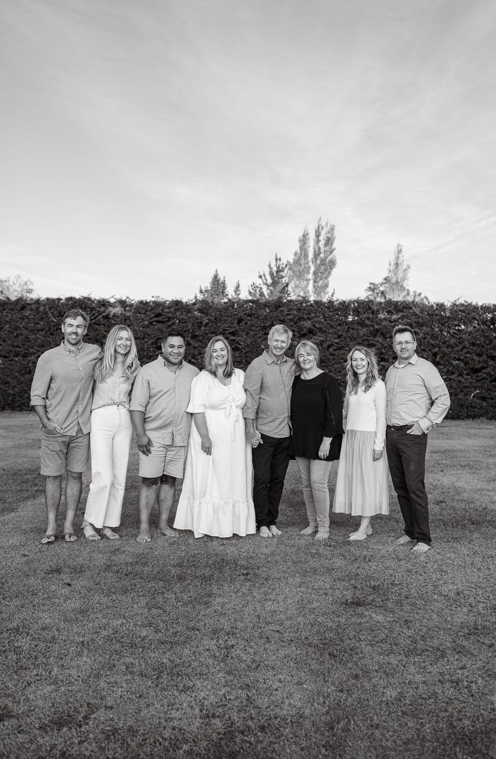 Black and white portrait of family members lined up outdoors wearing coordinated casual attire.