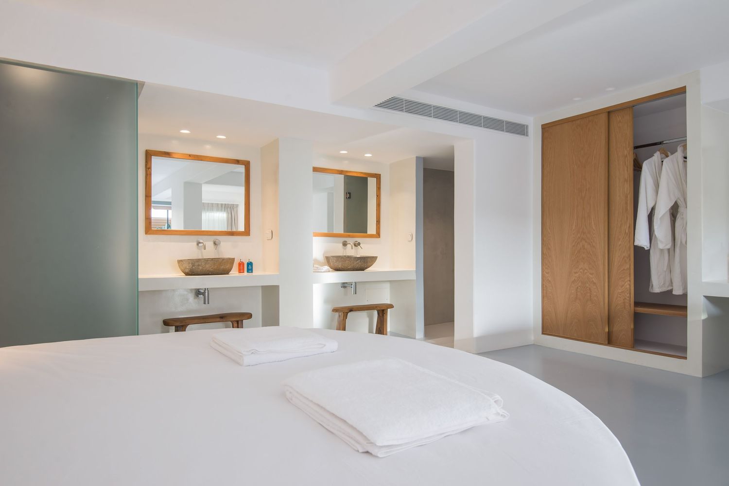 Modern minimalist bedroom with sage green accent wall, built-in vanity stations, and light wood wardrobe storage.
