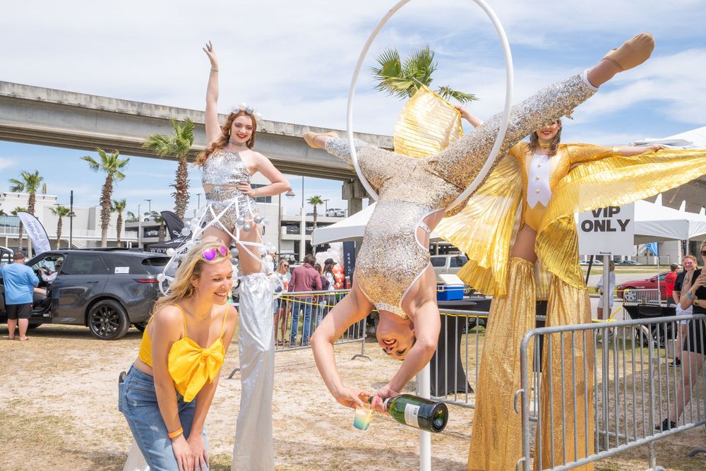 Acrobatic performers in metallic costumes entertaining crowds at an outdoor festival.