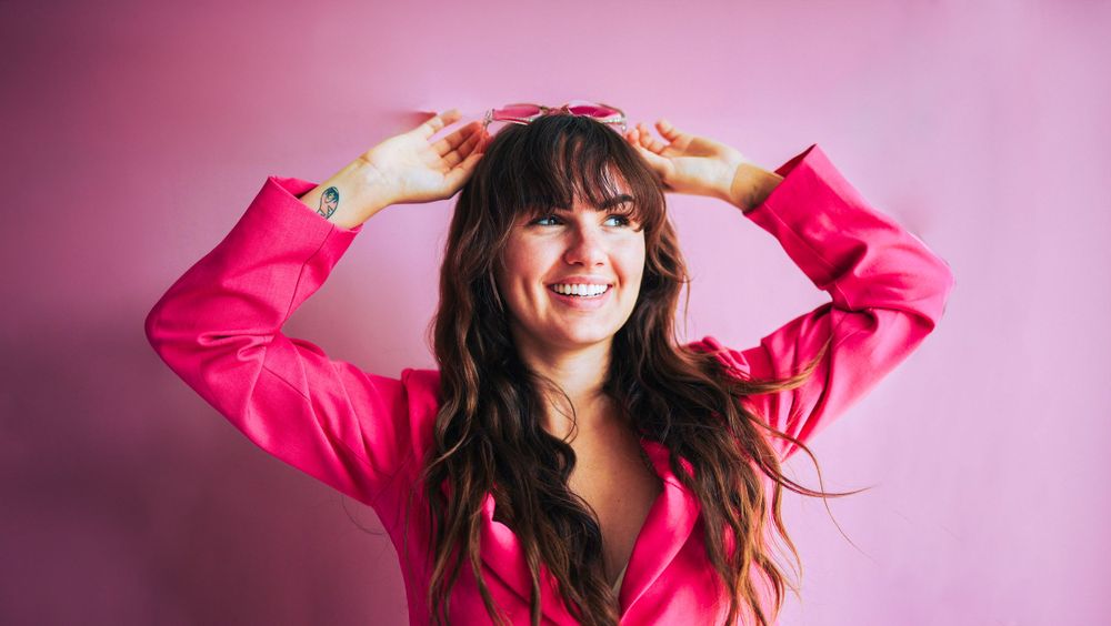 Joyful movement captured in pink suit against soft rose-colored background.