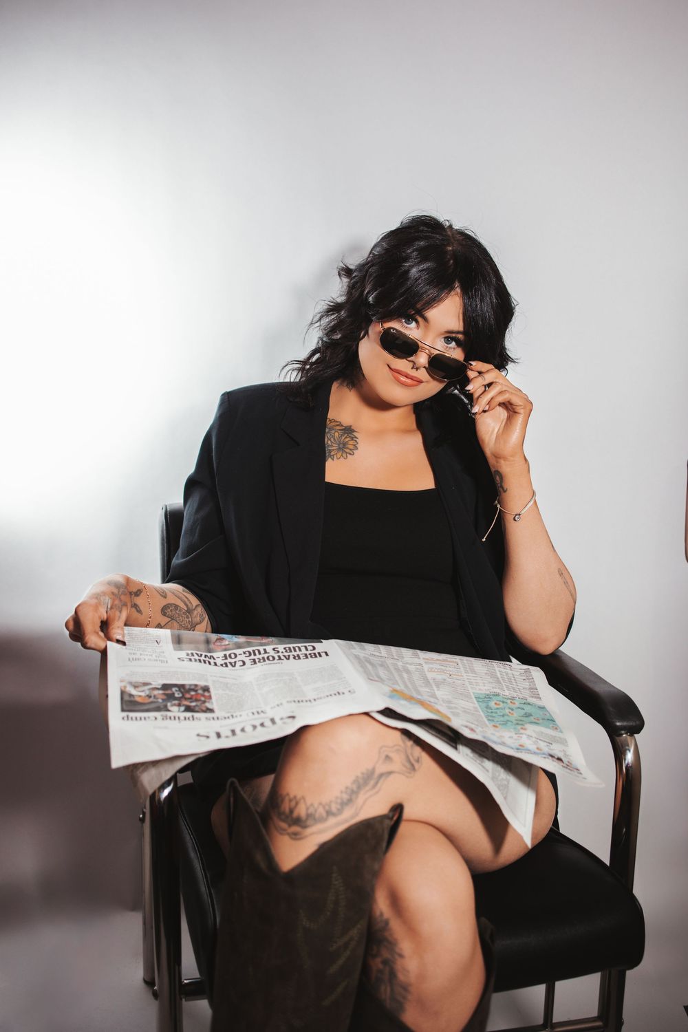 A person in black attire and sunglasses poses artistically while reading a newspaper in a sequence of moody photographs.