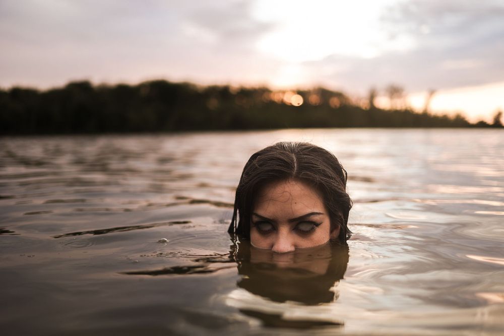 Serene sunset water portraits with silhouetted figures emerging from calm waters.