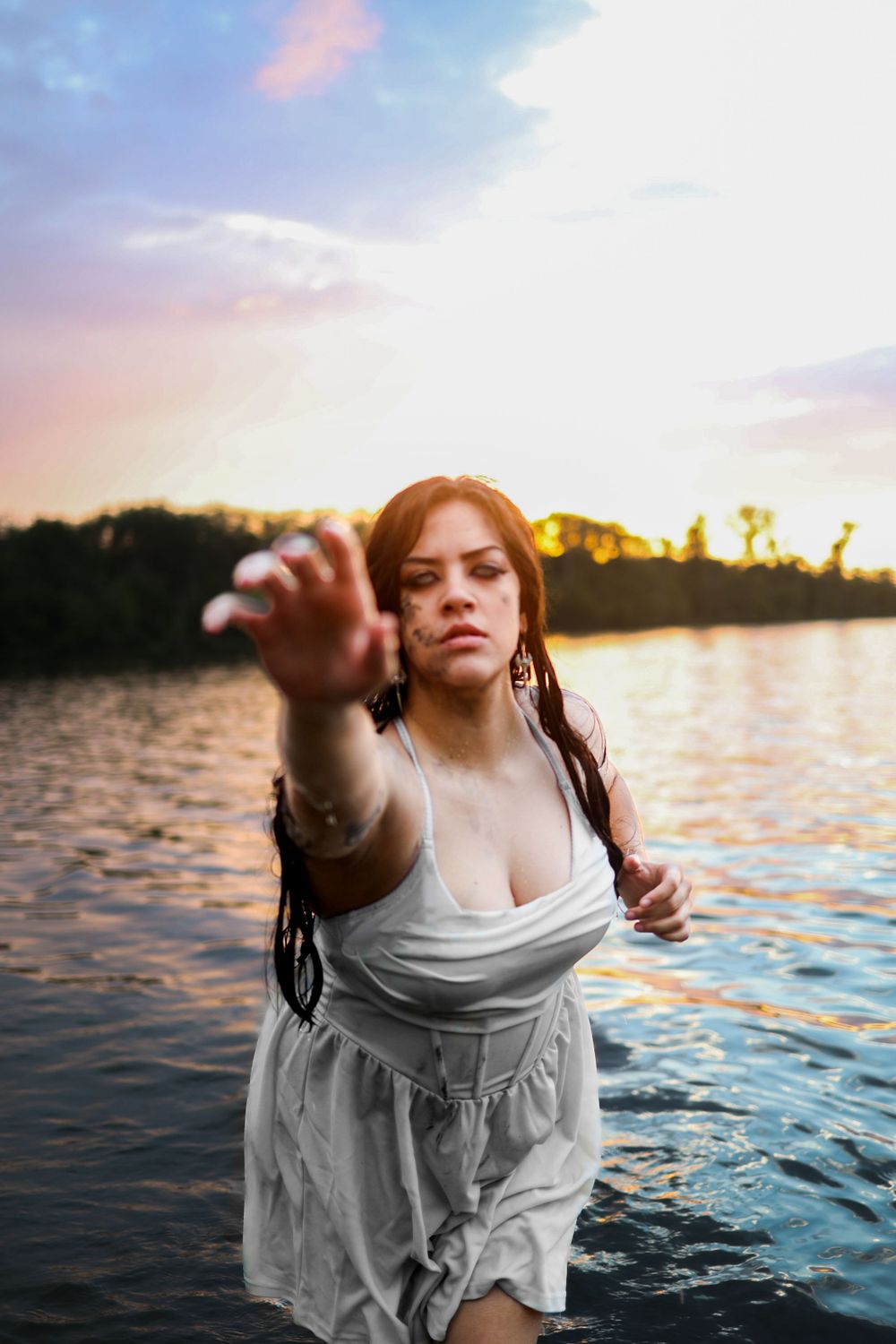 Dreamy sunset water photoshoot with flowing white dress and reaching gestures.