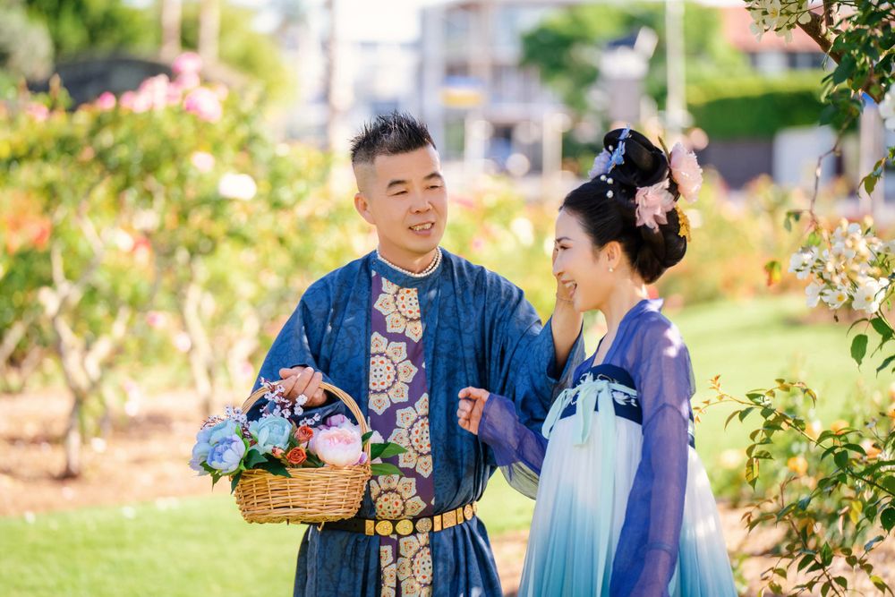 Dynamic natural sunlight portrait of a couple hugging and dancing in Tang Dynasty Hanfu among blooming roses, by Imagine Image Studio.