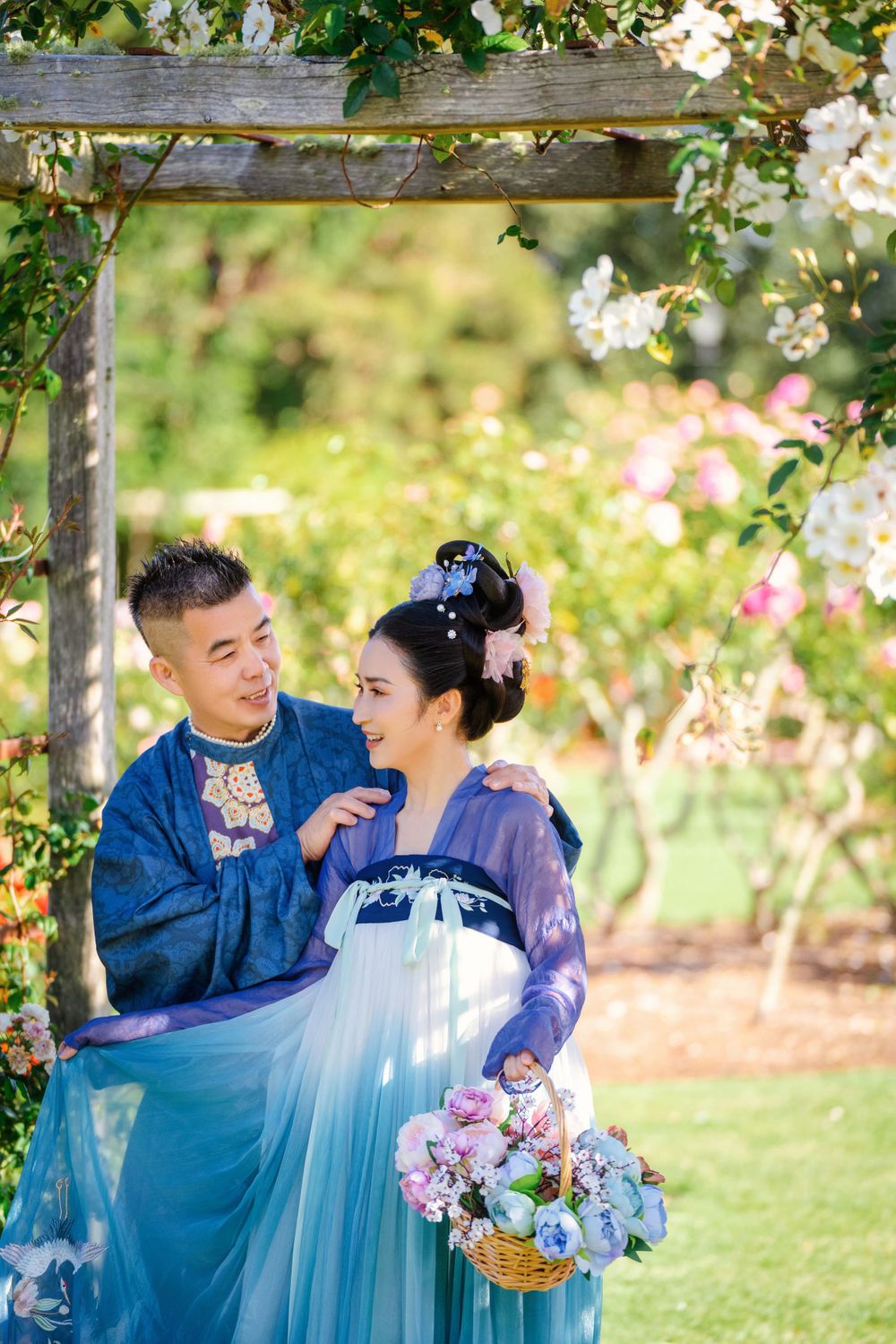 Dynamic natural sunlight portrait of a couple hugging and dancing in Tang Dynasty Hanfu among blooming roses, by Imagine Image Studio.