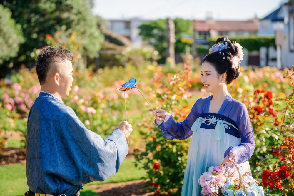 Dynamic natural sunlight portrait of a couple hugging and dancing in Tang Dynasty Hanfu among blooming roses, by Imagine Image Studio.