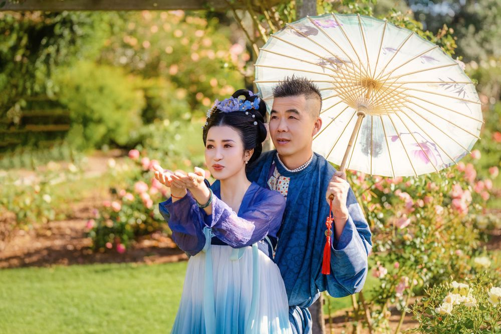 Dynamic natural sunlight portrait of a couple hugging and dancing in Tang Dynasty Hanfu among blooming roses, by Imagine Image Studio.