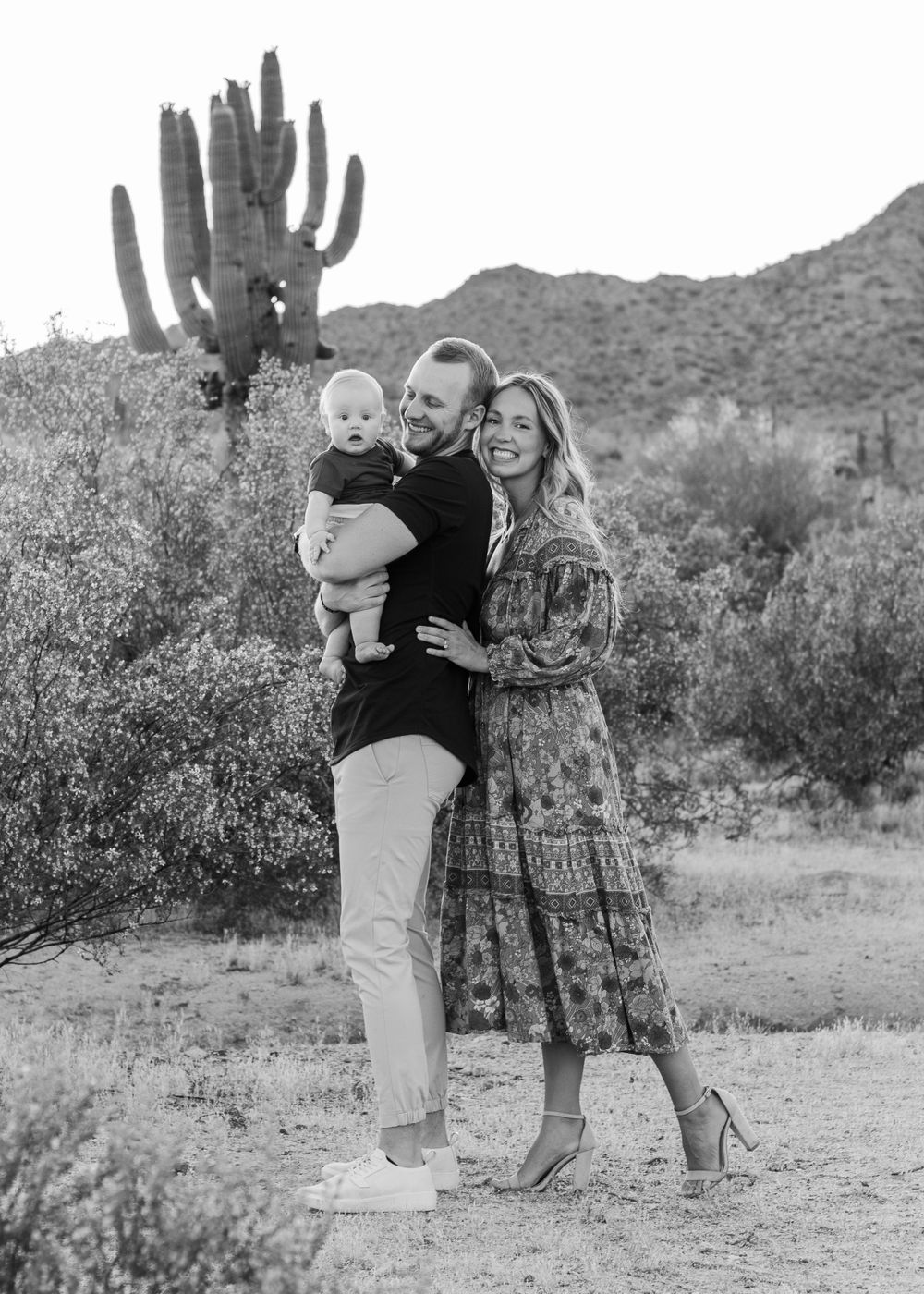 Black and white family portrait in desert landscape with saguaro cactus.