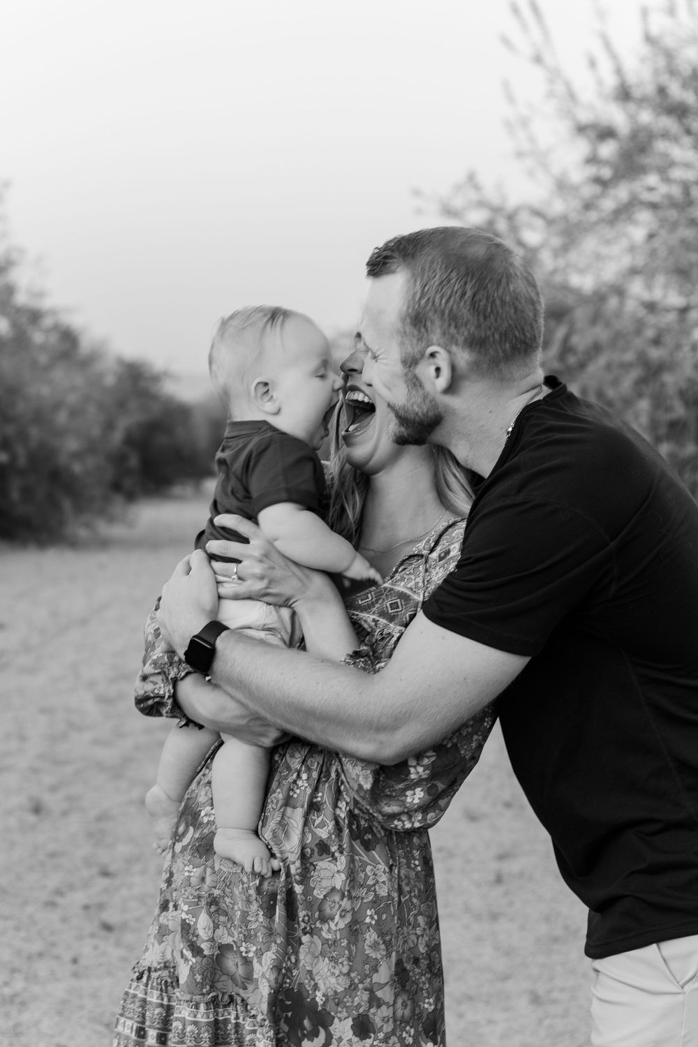 Black and white photo of family sharing intimate moment outdoors.