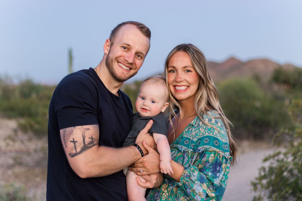 Family portrait in desert landscape with saguaro cactus at sunset.