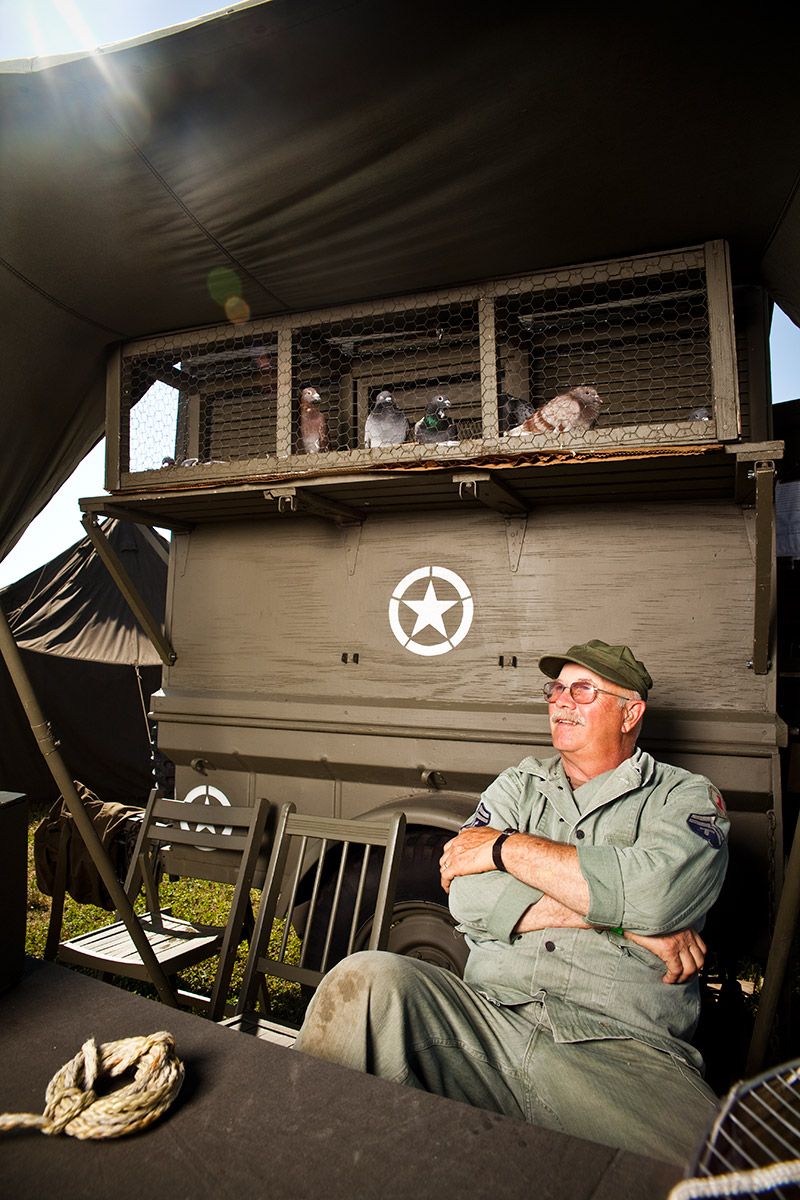 Man in military uniform relaxing beside WWII army vehicle with star insignia.