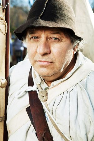 Portrait of man in colonial period costume with felt hat near tent.