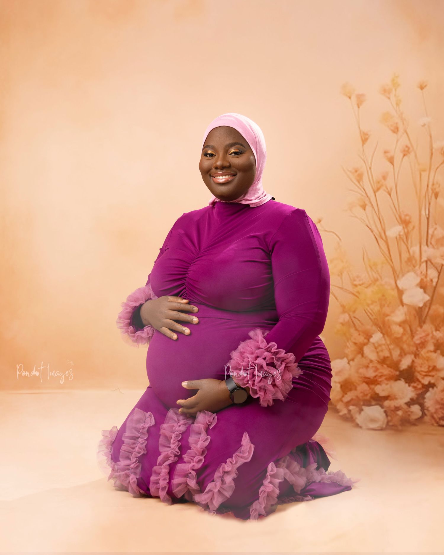 Maternity photoshoot with person wearing purple dress against peach floral background.