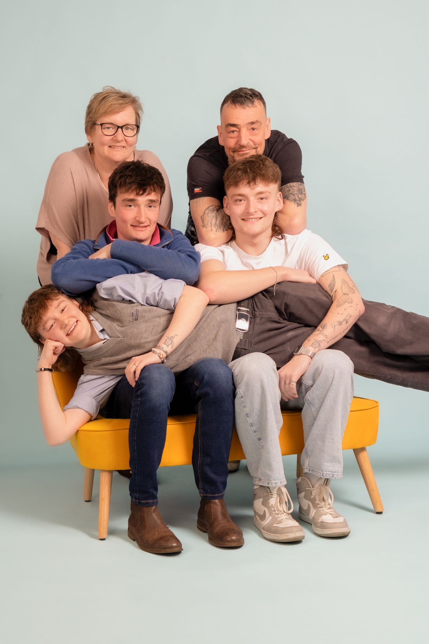 Studio family portrait with four people seated together against white background.