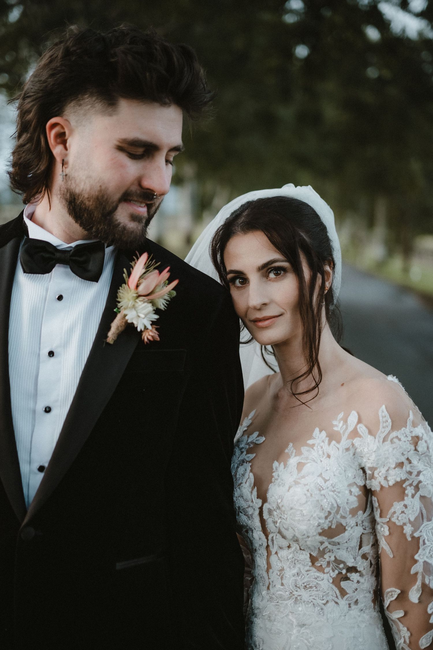 Romantic wedding couple in formal attire sharing intimate moments against a dark outdoor backdrop.