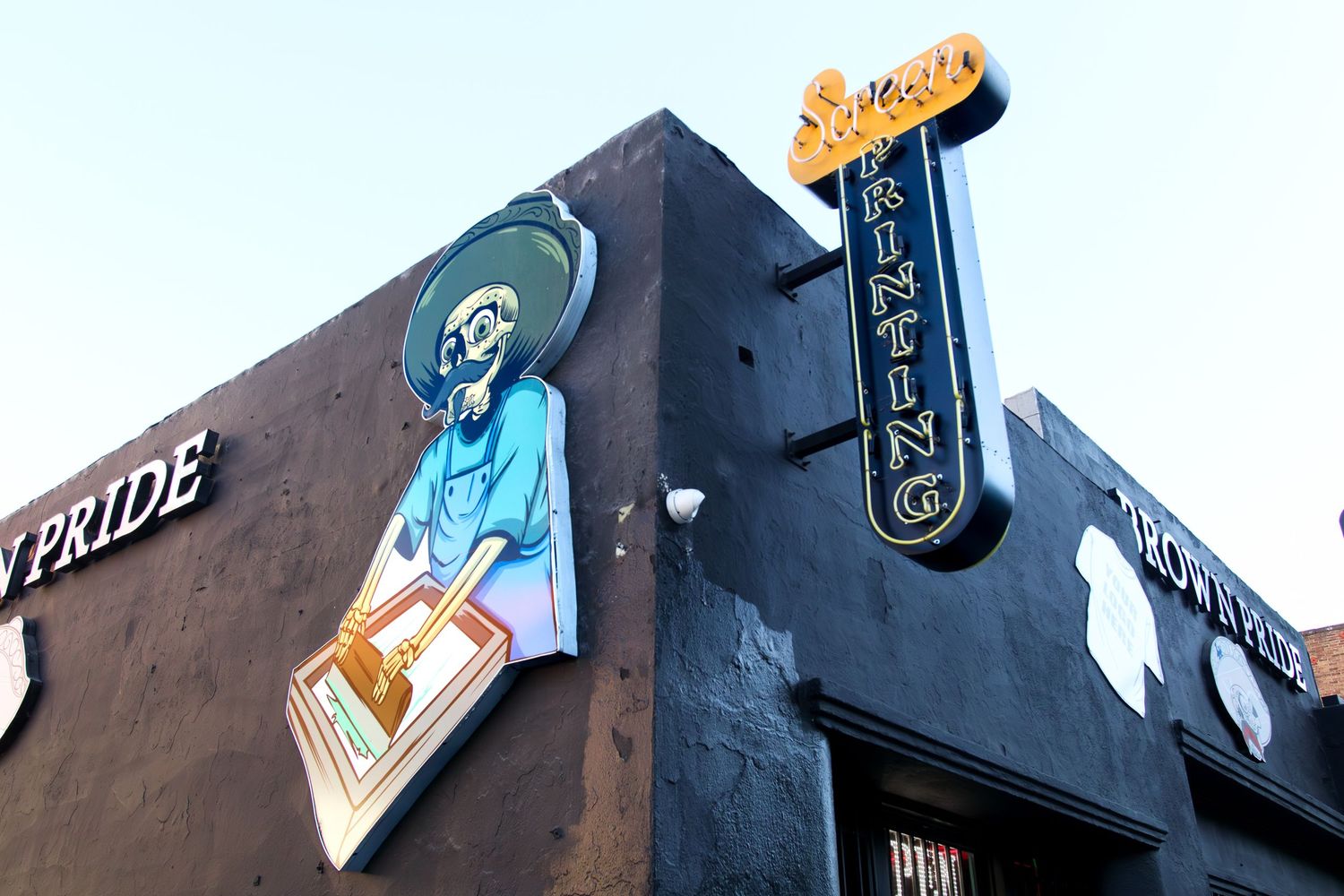 Colorful mural of skeleton mariachi musician decorates exterior wall of urban building with signage.