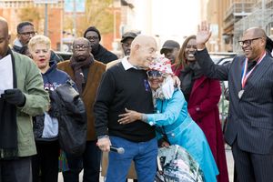 Diverse group of people gathered outdoors on a city street, smiling and embracing during a community celebration event.