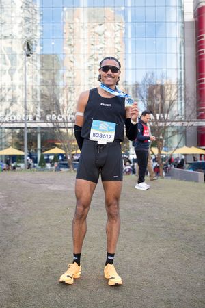 Runner wearing bib B28617 proudly displays finisher medal after completing a marathon race outdoors.