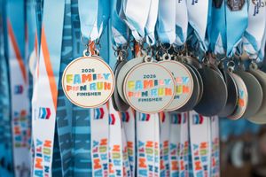 2026 Family Fun Run finisher medals hanging on blue and orange ribbons at a running event.