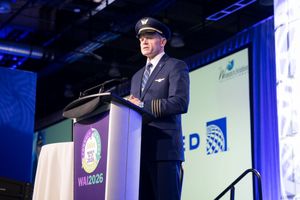A United Airlines pilot in uniform speaks at a podium during the WAI 2026 aviation conference on a blue stage.