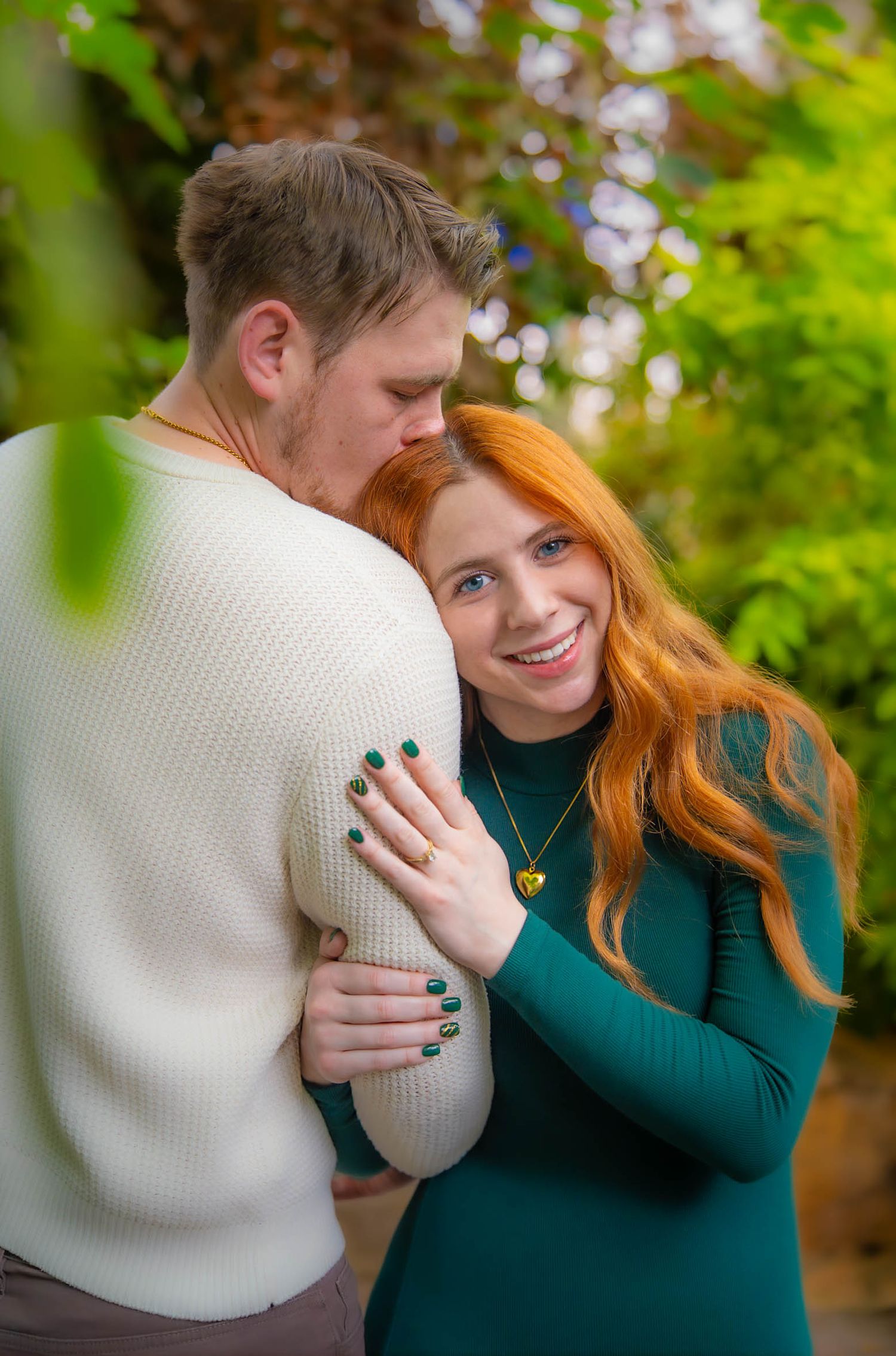 Couple engagement photoshoot embraces outdoors with green foliage. Quad Cities Photography