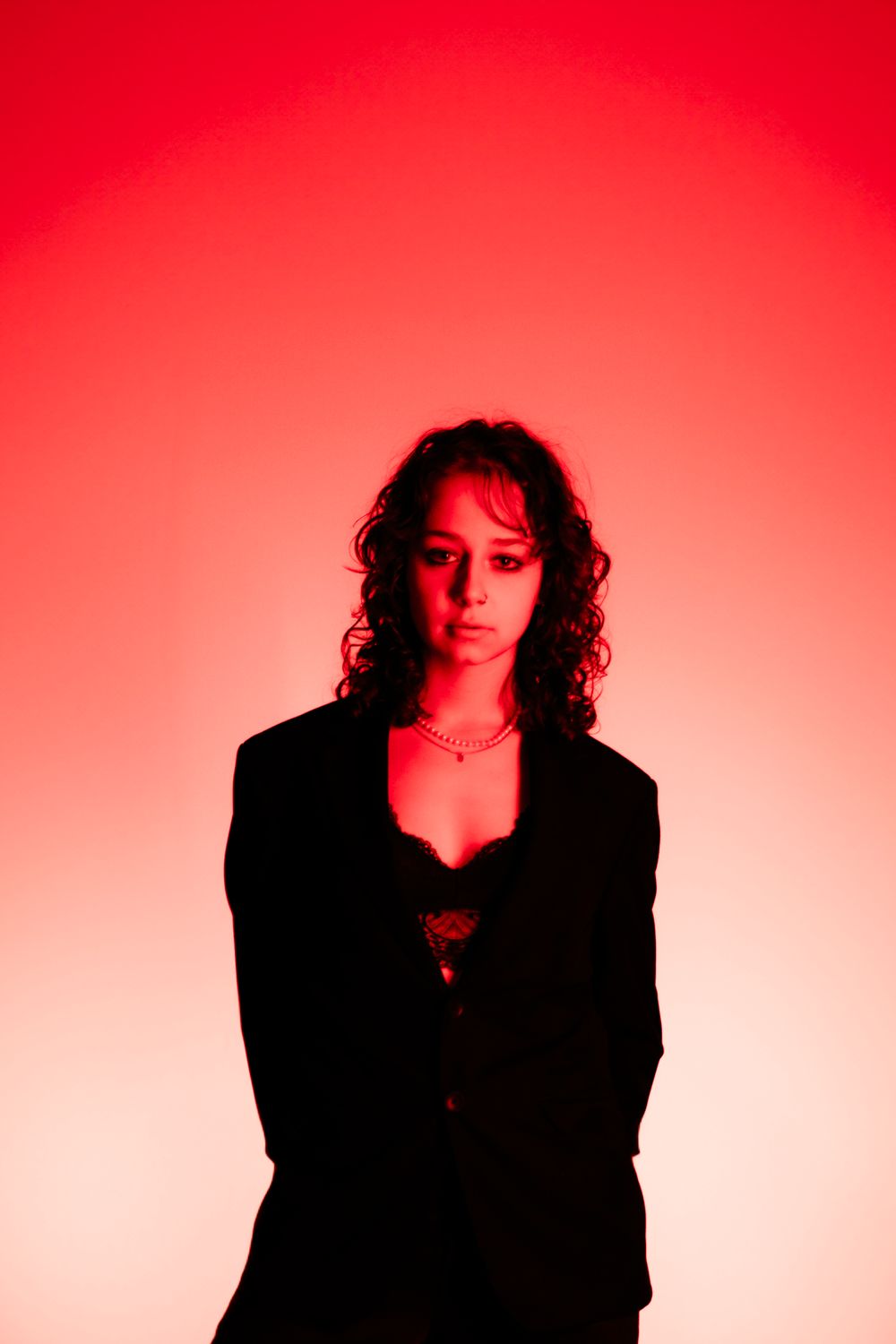 Artistic portrait against a vibrant red background with dramatic shadow effects.