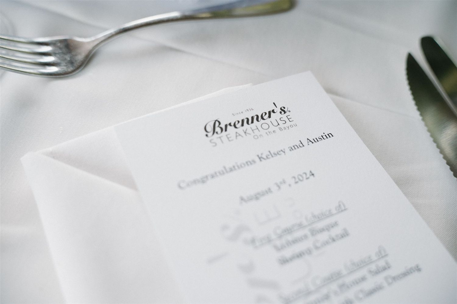 A close-up view of a restaurant menu at Brennan's with a fork visible on white tablecloth.