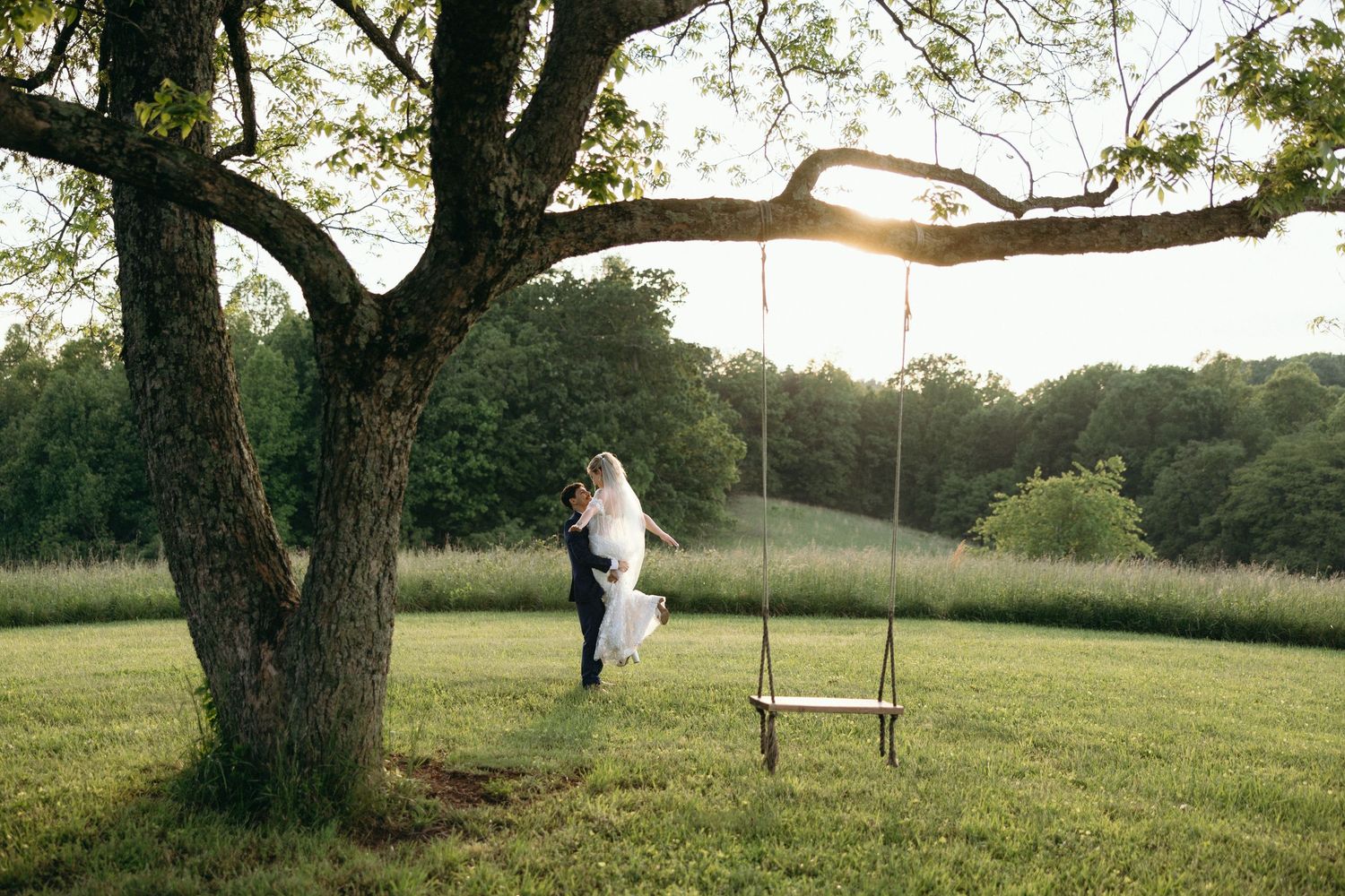 A tree swing hangs in a peaceful meadow during golden hour with long shadows cast across the grass. Twickenham House Wedding Photographer