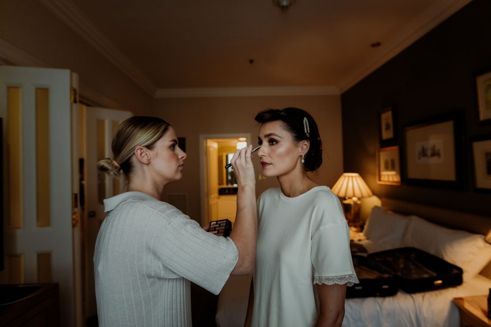 Two people having a quiet conversation in a warmly lit hotel room.