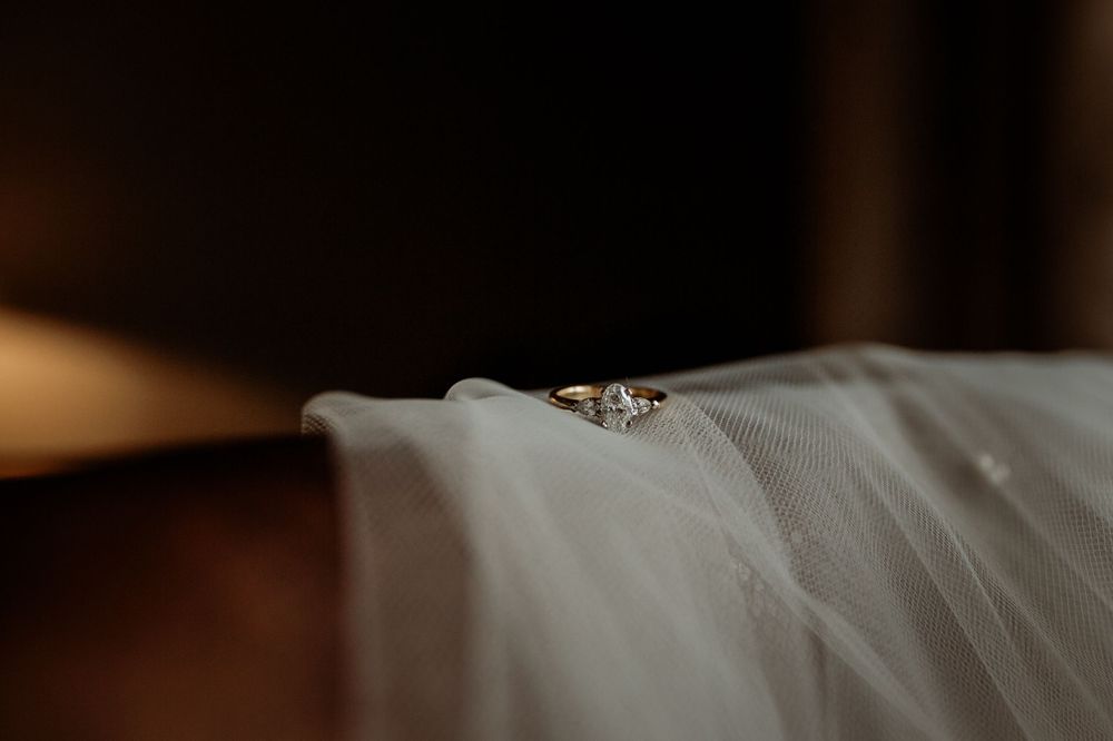 Wedding rings resting delicately on white tulle fabric in soft lighting.