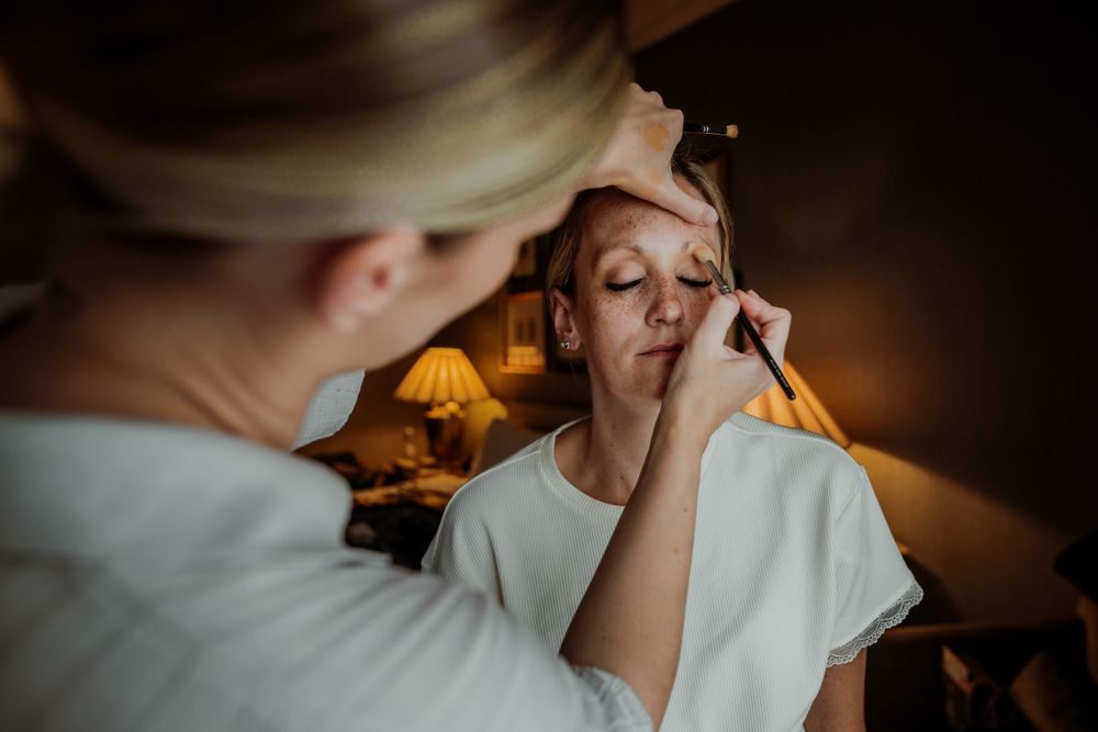 A detailed shot of wedding makeup application in atmospheric golden lighting.
