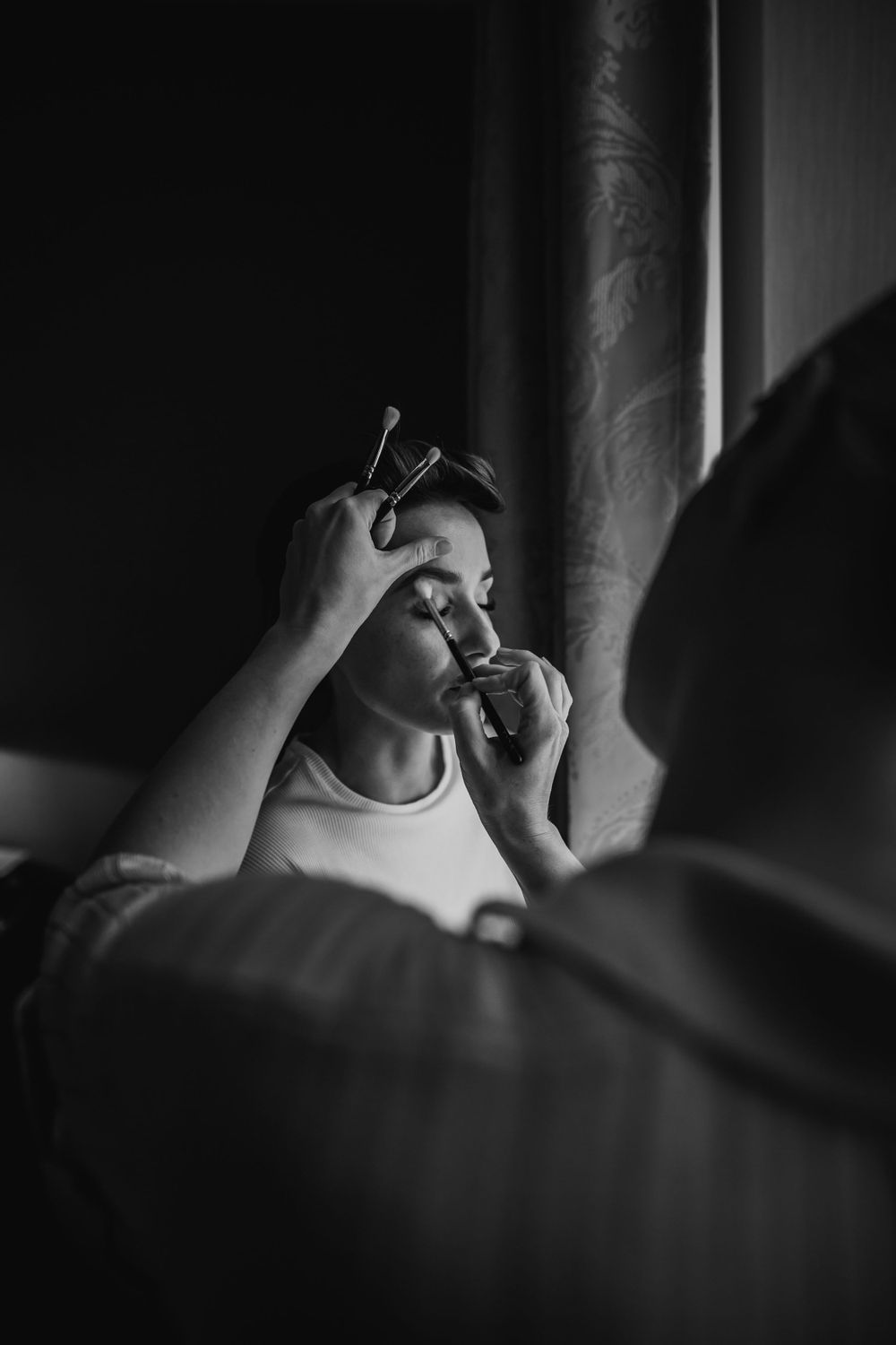 Dramatic black and white photo of makeup application in natural light.