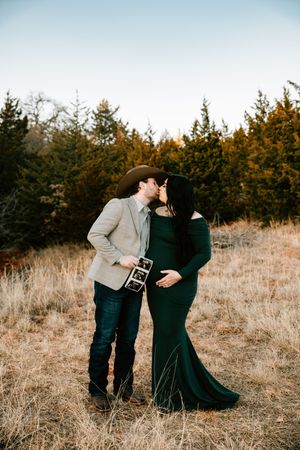 A western couple pose for their maternity photo session at Arcadia Lake outside of Arcadia, Oklahoma.