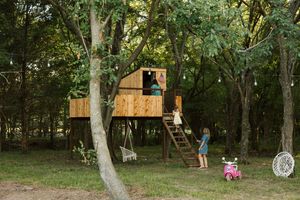 Extended family photo session with three children climbing a tree house and being looked after by mom on their family ranch in Council Hill.