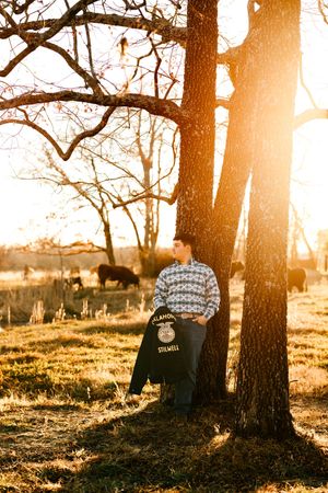 A Hulbert High School senior poses with his FFA jacket on his family's cattle farm outside of Hulbert, Oklahoma.